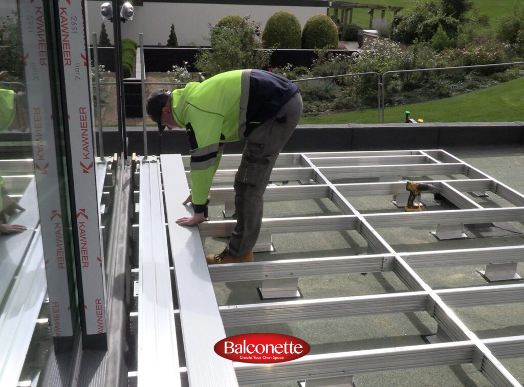 BalcoDeck non-penetrative balustrade and decking substructure resting on bearing pads above a flat roof membrane