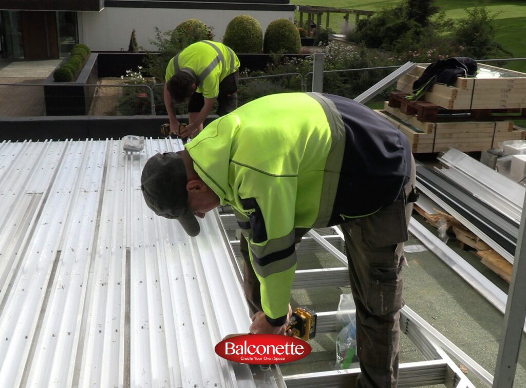Two installers fixing BalcoDeck aluminium decking boards to the substructure on a roof terrace